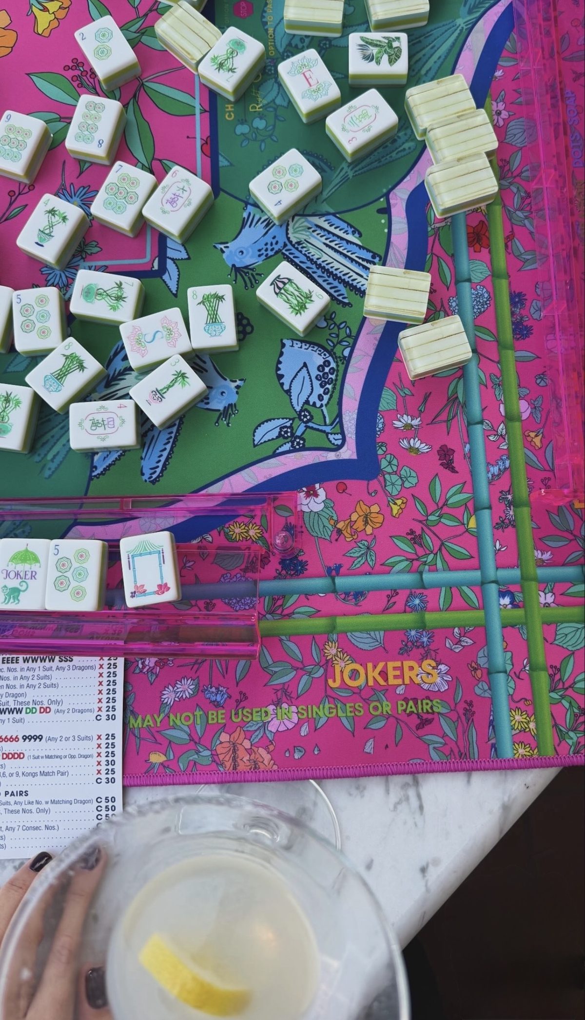 Mahjong tiles on a pink and green floral mat